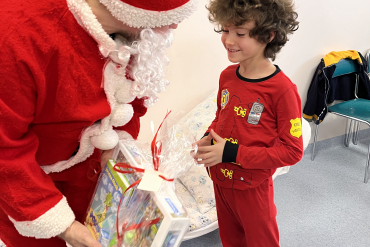 Na zdjęciu uśmiechnięty chłopiec w stronę którego poochyla się św. Mikołaj trzymający w ręku prezent.